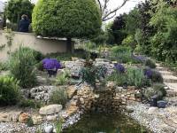 Im letzten Abschnitt des Bachlaufes flie&szlig;t das Wasser &uuml;ber eine Natursteinplatte laut pl&auml;tschernd in den Gartenteich (in Paris).